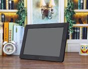 A black photo frame sitting on a table next to a clock. A black photo frame sitting on a table next to a clock.