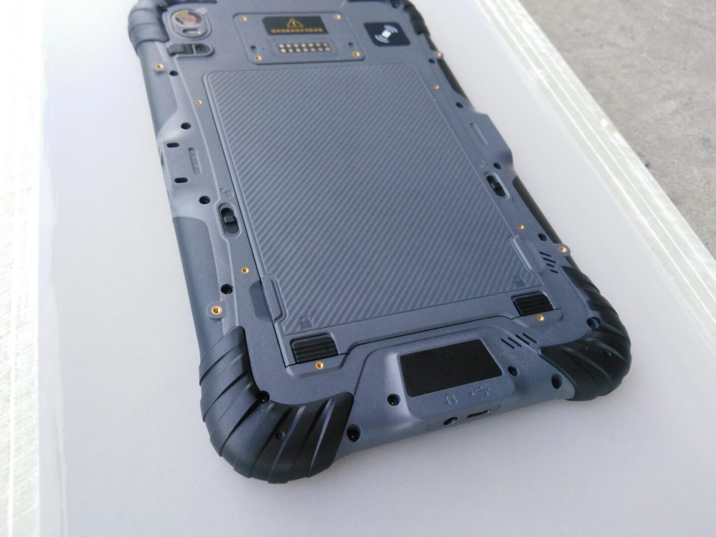 The back of a GK-ST8-QC 8" Android Rugged Tablet with 1D/2D Barcode scanner on a table. The back of a GK-ST8-QC 8" Android Rugged Tablet with 1D/2D Barcode scanner on a table.